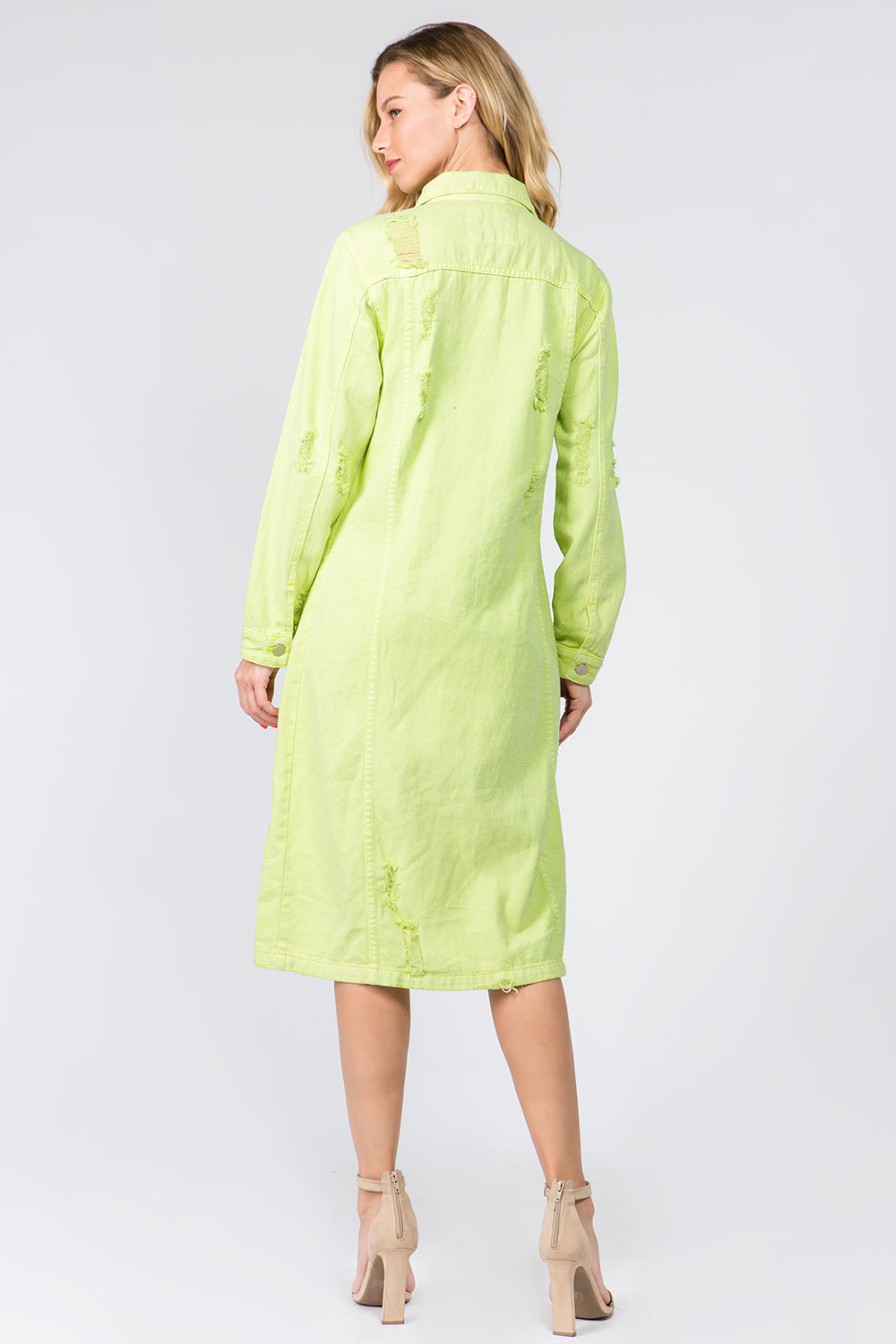 A woman wearing the American Bazi Button Up Distressed Denim Dress in light green, with its long sleeves and distressed detailing, pairs it with beige high-heeled sandals as she poses against a plain white background, facing away from the camera.