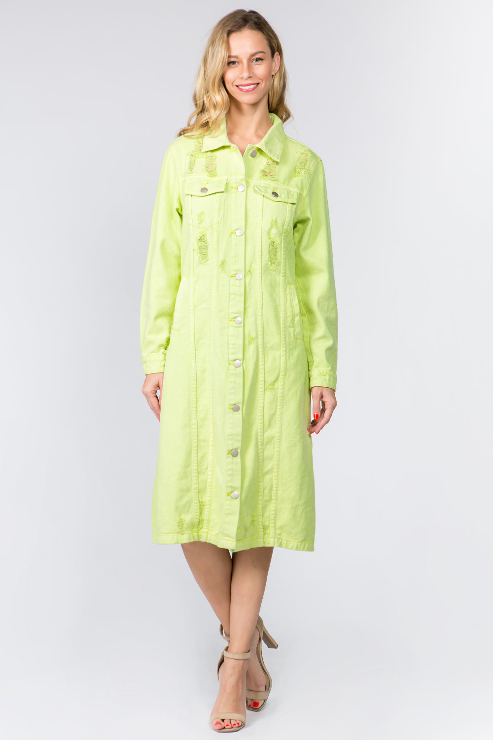 A person in an American Bazi Button Up Distressed Denim Dress stands smiling in a neutral pose. The knee-length, long-sleeved, lime green dress features embroidered patterns and a collar. Paired stylishly with beige high-heeled sandals against a plain white background, it creates a chic ensemble.