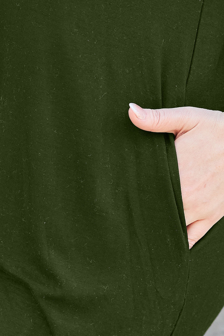 A close-up of a person wearing the Basic Bae Full Size Round Neck Short Sleeve Dress with Pockets in dark green, with their right hand in the pocket. The polyester-blend fabric appears soft and slightly textured, making it ideal for a cold machine wash.