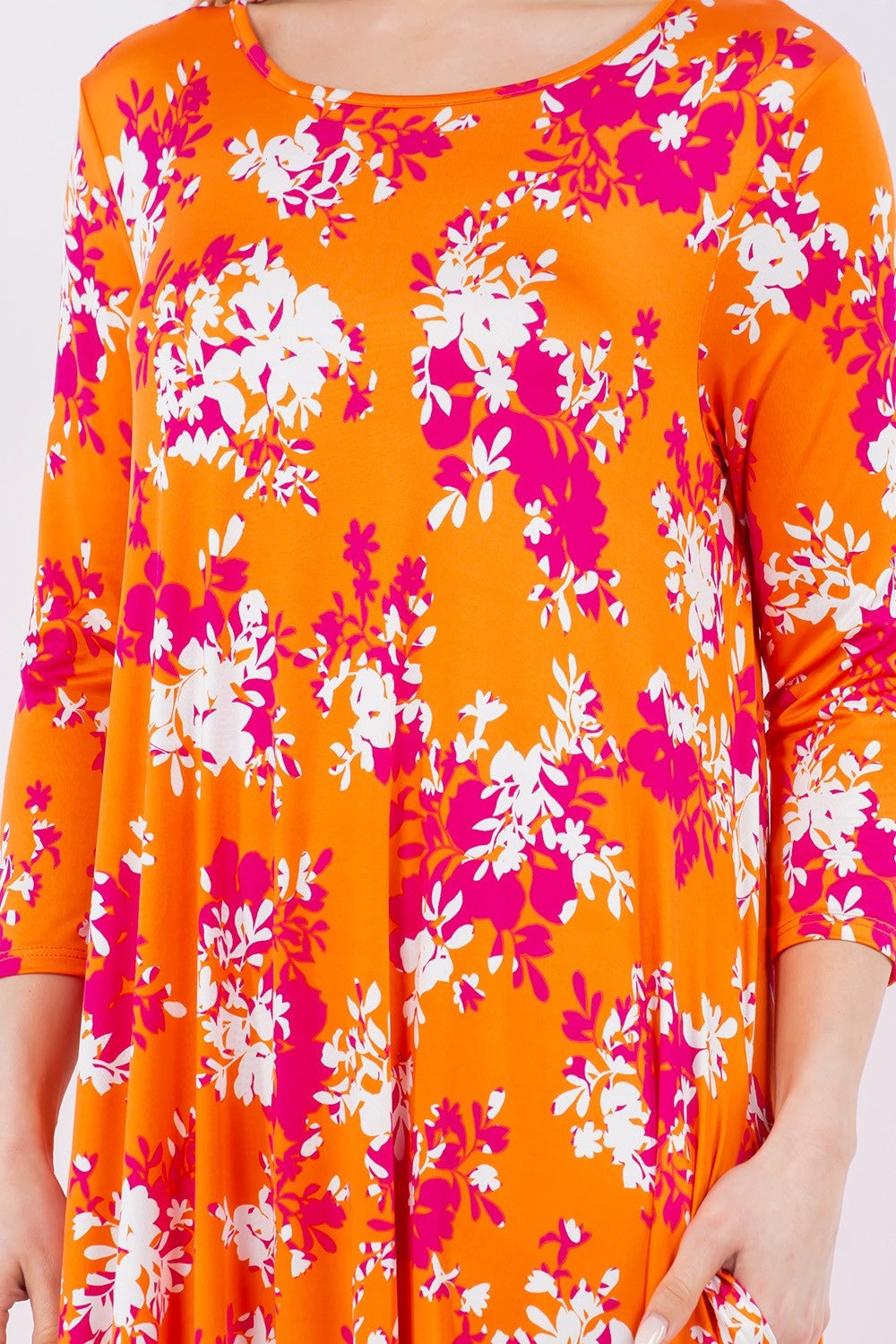 The Celeste Full Size Pick-Up Hem Asymmetric Floral Midi Dress features a vibrant orange color with white and pink floral patterns, three-quarter sleeves, and a flowing pick-up hem design for a modern touch.