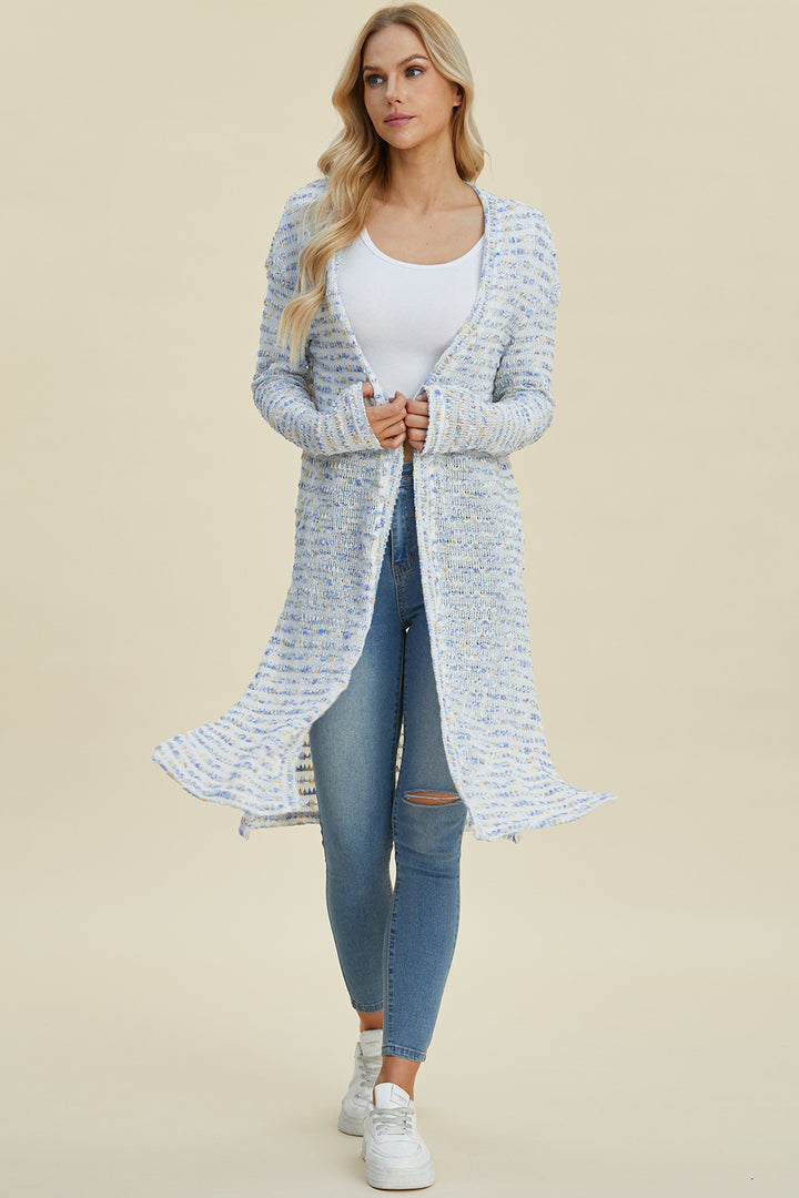 A person with long blonde hair is wearing a white tank top, the Double Take Full Size Open Front Longline Cardigan in blue and white openwork, ripped blue jeans, and stretchy white sneakers, standing and posing against a light beige background.