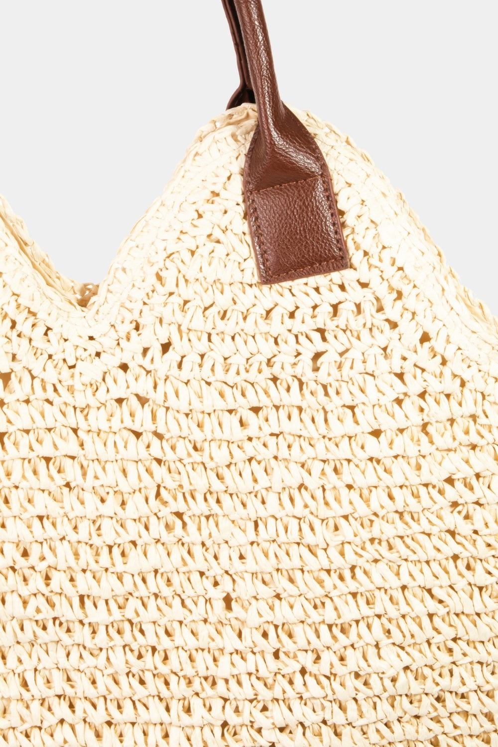 The Fame Straw Braided Faux Leather Strap Shoulder Bag features a prominent beige straw texture with intricate weaving patterns. It includes dark brown faux leather straps and a decorative handle attachment for added detail.