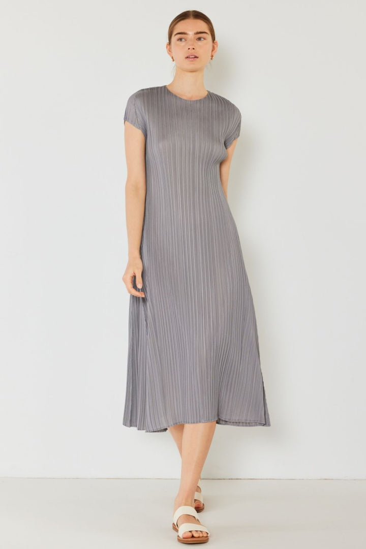 Wearing the Marina West Swim Pleated Cap Sleeve A-Line Dress in gray, exuding feminine charm against a white backdrop, the person completes their look with stylish white sandals.