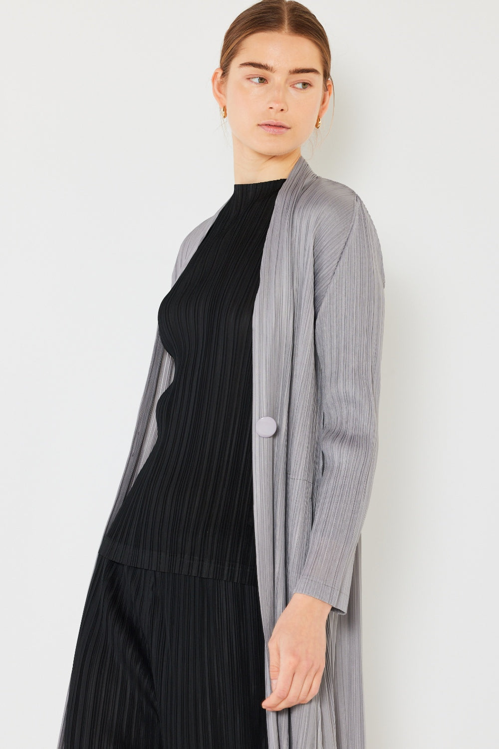 Wearing the Marina West Swim Pleated Long Sleeve Cardigan, a person with long hair showcases the versatile light gray cardigan against a plain white background, gazing to the side.