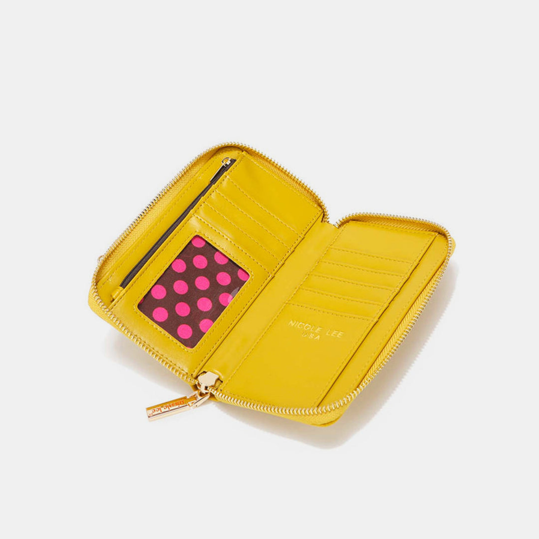 The Nicole Lee USA 2 Piece Phone Case Crossbody Wallet is an open yellow zipper wallet, made of vegan leather, featuring a cardholder slot with a pink card with black polka dots, a zippered pocket, and Nicole Lee USA printed inside. It is showcased on a plain white background.