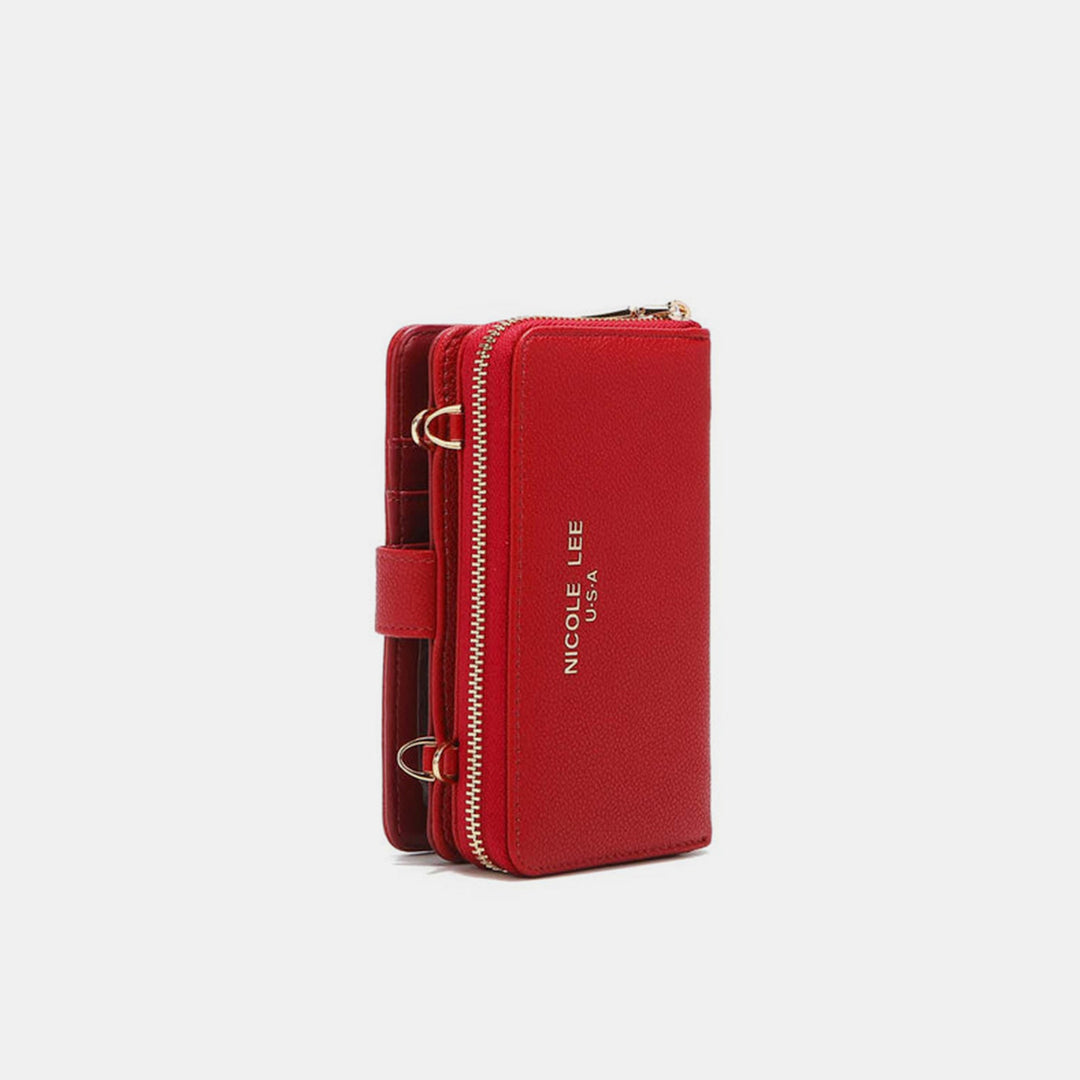 A vegan leather red crossbody wallet with gold zipper detailing, featuring NICOLE LEE USA embossed in gold on the front. This compact, vertical design includes a strap and metal rings for attachments, making it perfect for essentials.