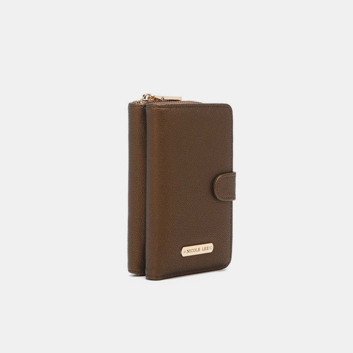 The Nicole Lee USA 2 Piece Phone Case Crossbody Wallet is a sleek brown accessory with a gold zipper, buttoned strap closure, and a small gold plate on its vegan leather front. It is elegantly displayed from an angle against a plain light background.