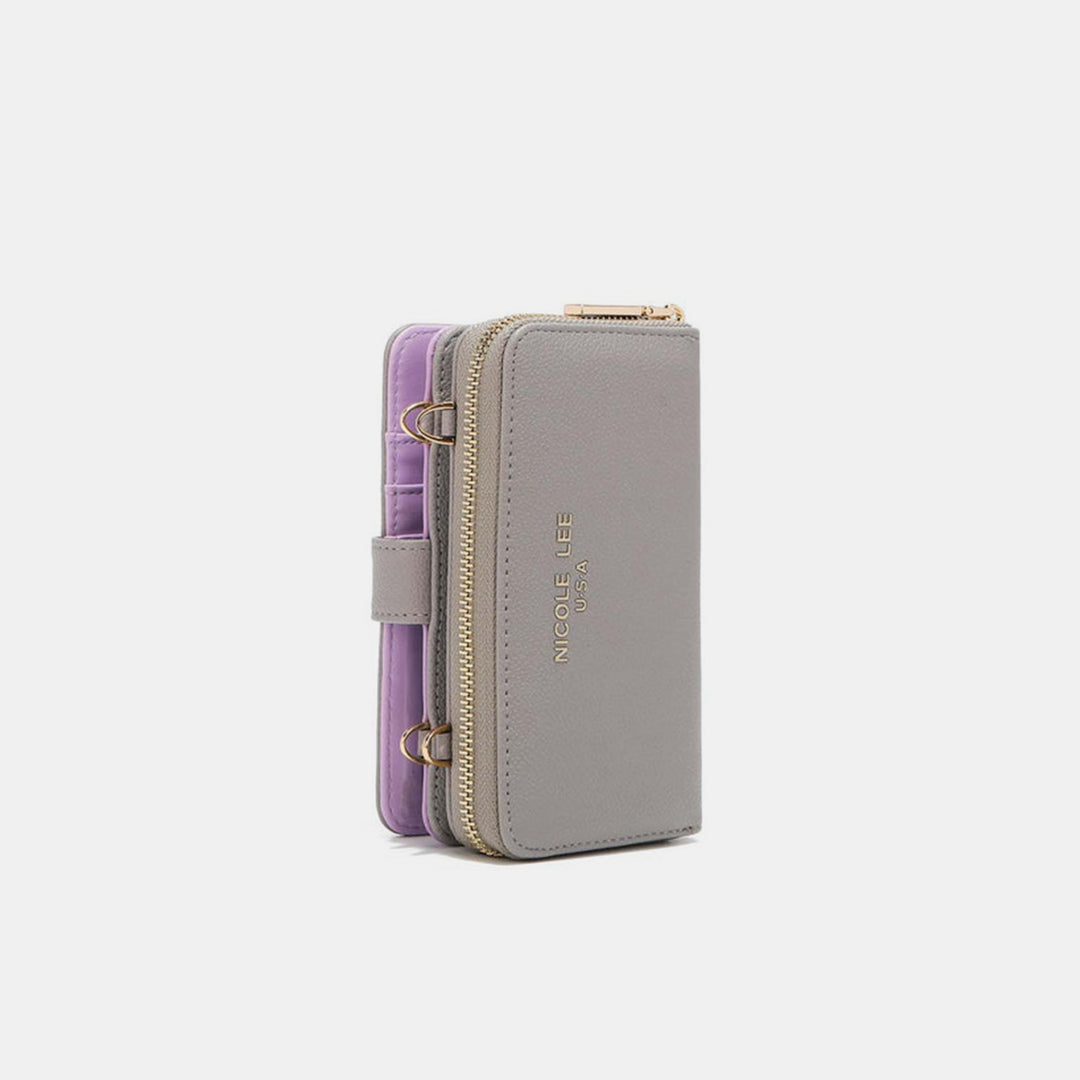 The Nicole Lee USA 2 Piece Phone Case Crossbody Wallet is a chic gray accessory with gold zippers and accents, featuring a branded logo. Made from vegan leather, it has a detachable strap loop and purple interior, set against a light background.