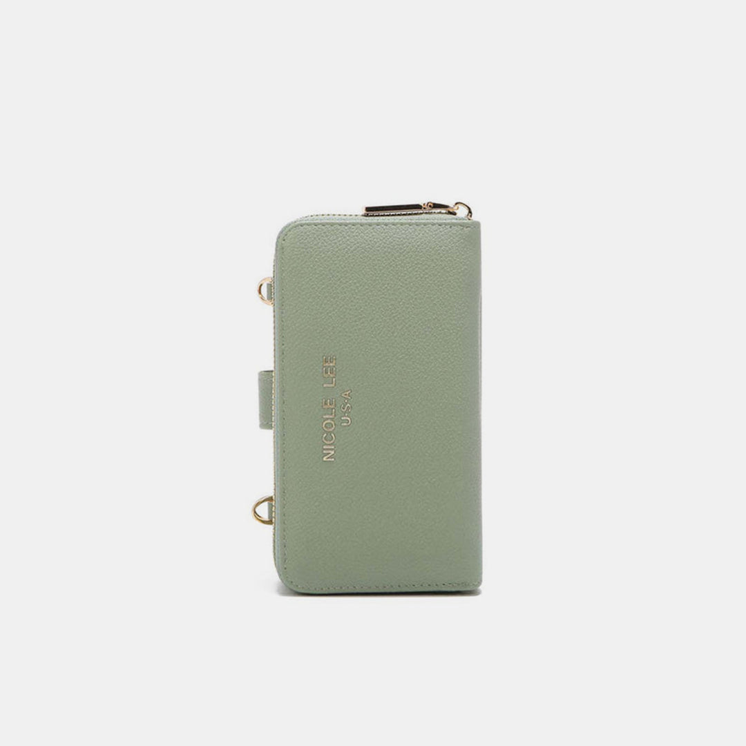 A sage green Nicole Lee USA crossbody wallet with zip closure, gold accents, and text on the front. Made from vegan leather, it has a textured finish and two side gold rings.