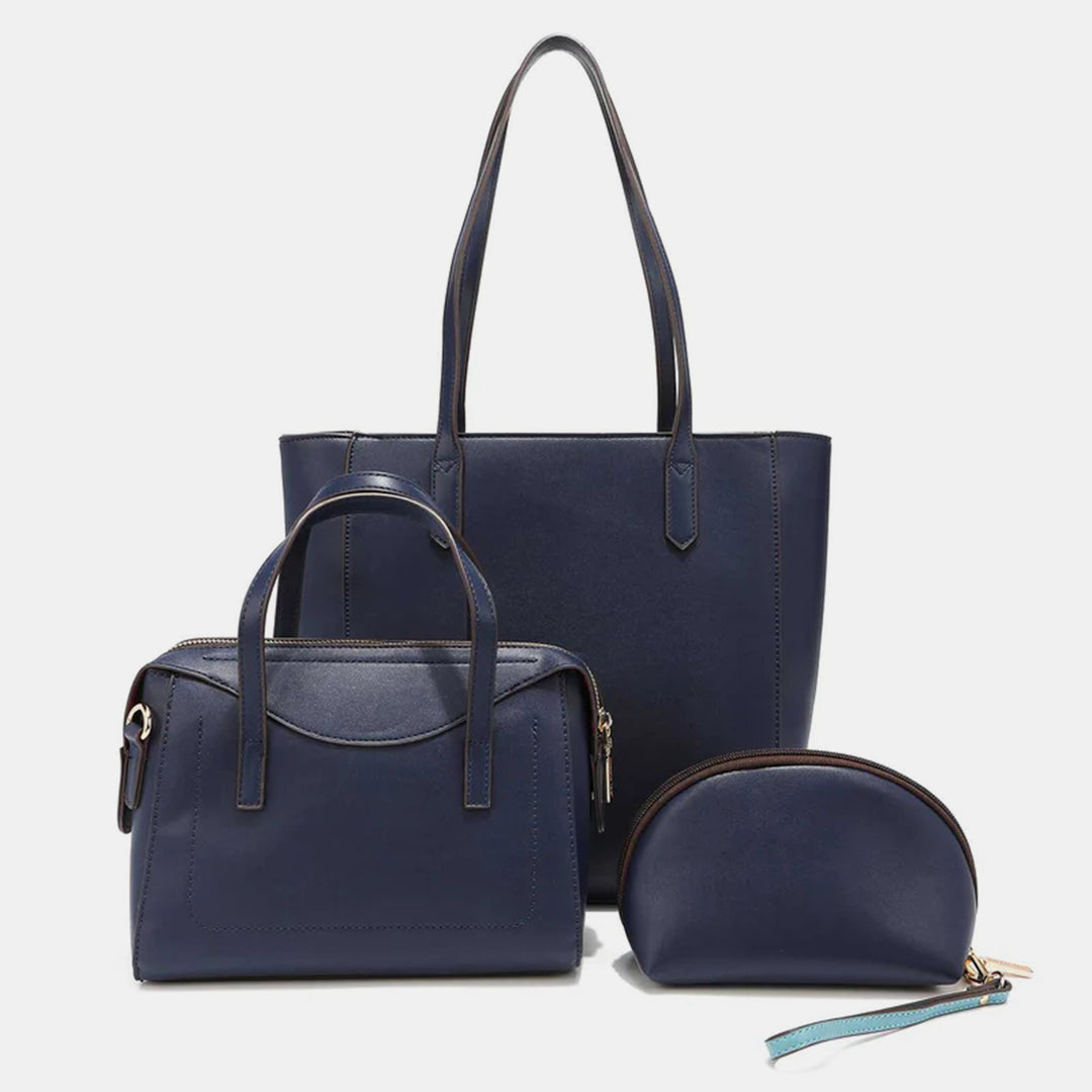 The Nicole Lee USA 3-Piece Color Block Handbag Set features stylish dark blue vegan leather bags against a light backdrop: a large tote, color-block handbag, and compact pouch with zipper closure, showcasing functional and elegant design.