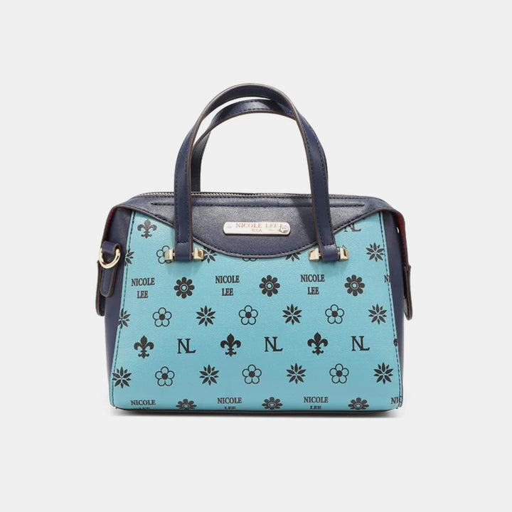 A chic Nicole Lee USA handbag in blue with dark handles and floral patterns, crafted from vegan leather. Features NICOLE LEE, NL initials in black, and a gold-toned logo plate, perfect for any color block collection.