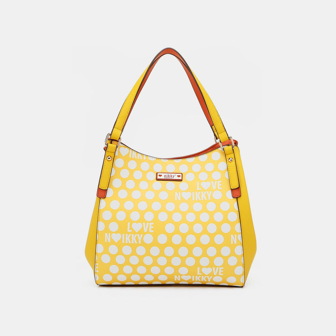 The Nicole Lee USA Contrast Polka Dot Handbag is a spacious bag made from vegan leather, featuring LOVE NIKKY text, playful yellow polka dots, orange handles, and a small rectangular brand tag on the front for a stylish accent.