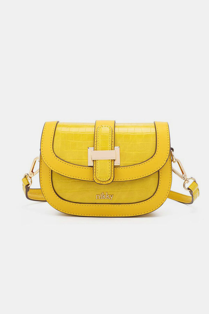 The Nicole Lee USA Croc Embossed Crossbody Bag is a chic small handbag in a vibrant yellow shade with a croc-embossed texture. Made from eco-leather, it includes a flap closure adorned with a decorative buckle and comes with an adjustable shoulder strap. The brand name Nikky is elegantly engraved on the lower front of the bag.