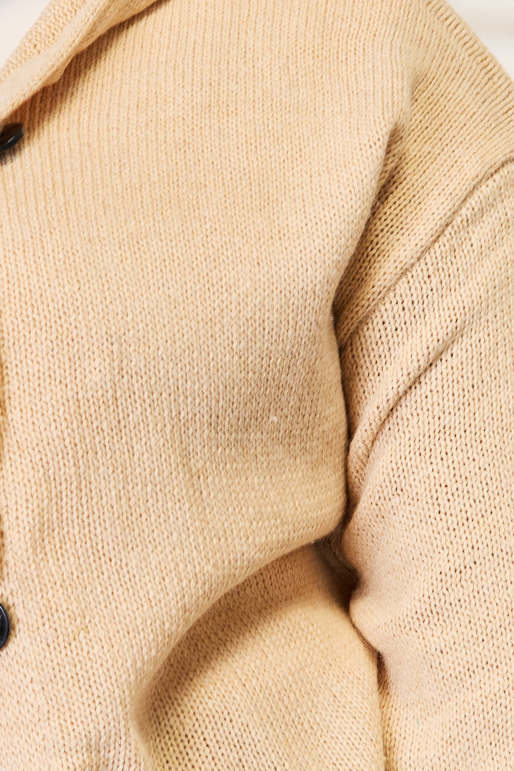 Close-up of the Woven Right Button-Down Long Sleeve Hooded Sweater in beige, featuring a prominent seam and black buttons. The fabric texture is highlighted, showcasing its detailed weave pattern.