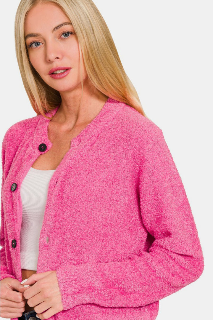 A woman with long blonde hair is wearing a bright pink Zenana Button Down Long Sleeve Sweater Cardigan over a white top. She is looking towards the camera with a neutral expression against a plain white background.