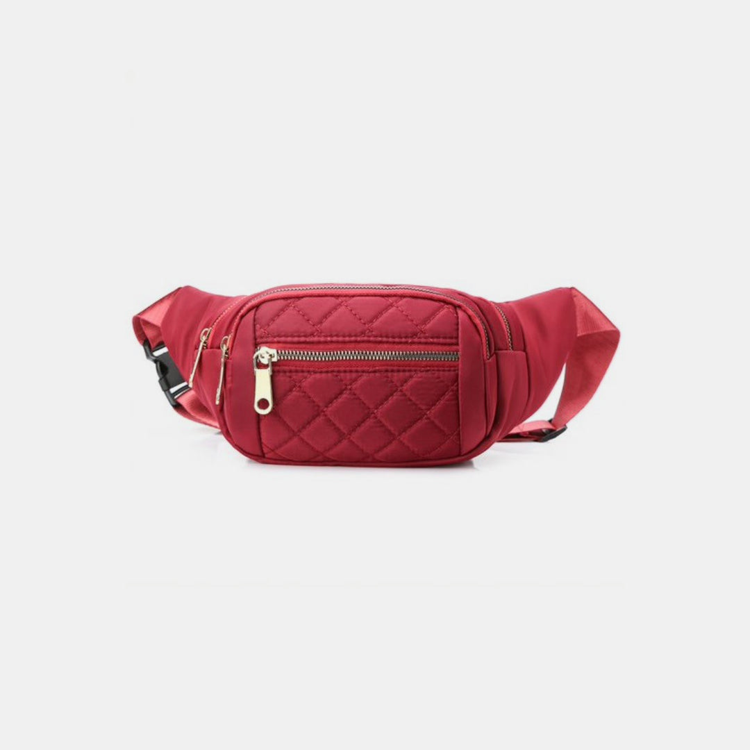 The Zenana Quilted Multi Pocket Waist Belt Bag, in a red quilted design, features a front zipper pocket with an elegant gold pull. Its adjustable strap ensures hands-free carrying and the bag is laid out horizontally. Set against a plain white background, this stylish bag merges fashion with functionality.