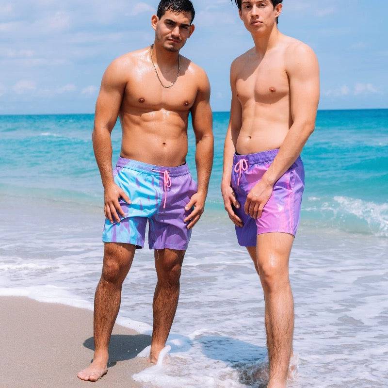 Two men standing in the surf showing the berry blast and candy splash color changing swim shorts available through Kameleon Swim